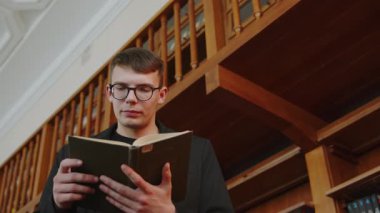 Huzurlu ve sessiz bir kütüphane ortamında ilgi çekici bir kitap okumaya dalmış genç bir adam. Medya