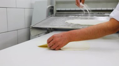 Yetenekli bir fırıncı, yoğun bir fırın ortamında elleri esnetip taze hamur kalıplarını ustalıkla çıkardı. Medya