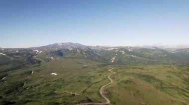 Göz kamaştırıcı manzaralı yeşil tepeler, dolambaçlı yollar ve berrak gökyüzünün altındaki görkemli dağlar. Medya