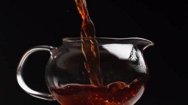 Cam çaydanlığa dökülen sanatsal bir çay sahnesi zengin rengini ve dokusunu güzel bir şekilde ön plana çıkarıyor. Medya