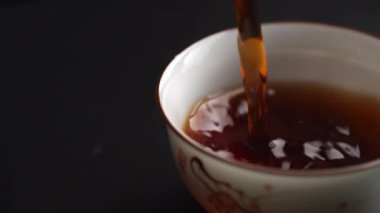 Zarif bir fincanın içine zarif bir şekilde dökülen büyüleyici bir çay sahnesi huzurlu ve huzurlu bir an sergiliyor. Medya