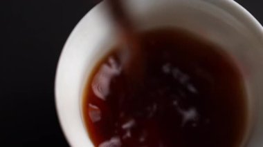 Güzel bir fincana ustalıkla dökülen sıcak çayın sıcaklığını ve rahatlığını yakalayan yakın çekim. Medya