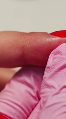 Yetenekli bir teknisyen zarif bir manikür deneyimi için ince aletlerle parlak kırmızı tırnak cilası sürer. Medya