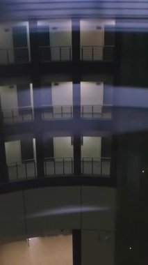 Aydınlatılmış balkonları olan modern bir binanın büyüleyici görüntüsü, gece atmosferine cazibe katıyor. Medya