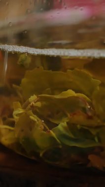 Videoda güzel bir çaydanlık ve canlı yeşil çay yapraklarıyla sakin bir çay içme deneyimi sergilenirken, rahatlatıcı bir dökümün altını çiziliyor. Medya