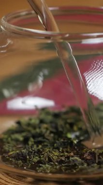 Video, yeşil çay güzelliğinin sergilendiği sakin bir çay yapma süreci sunuyor. Canlı yapraklar, sakinleştirici su sesleri ve kırsal ahşap bir masada bir fincana dökülen zarifliğe sahiptir. Medya