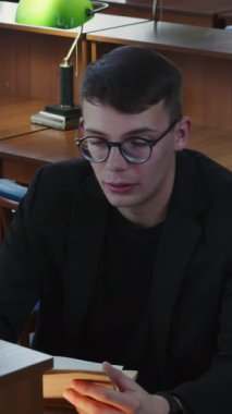 Kendini adamış bir öğrenci, kitaplar ve çalışma lambalarıyla çevrili sessiz bir kütüphane masasında okumaya dalmıştır. Medya