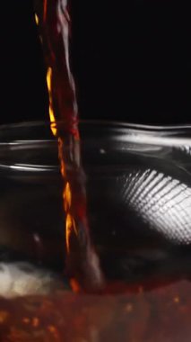 Göz kamaştırıcı ve güzel bir buharlı çay kadehi siyah arka planda cam bir çaydanlığa nazikçe dökülüyor. Medya