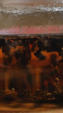 Bu video, sıcak bir ahşap zemin üzerinde zengin çay yaprakları olan cam bir çaydanlık ile huzurlu bir atmosfer yaratarak rahatlamayı yakalıyor. Medya