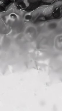 Bu siyah beyaz video, suyun dinamik güzelliğini gösteriyor, beyaz bir yüzeye çarpıyor, bir bardakta kabarcıklar ve kaynar su