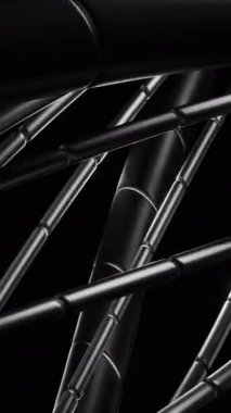 Karmaşık metalik yapı, siyah arkaplanda birbirine geçmiş siyah kablolar ile yavaşça dönüyor.