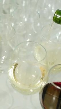 Garson festivalde bardaklara kırmızı şarap döker. Medya. Masanın üzerinde bir sürü kırmızı gözlük var. Şarap tatma.