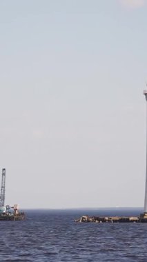 Gün boyunca açık denizde deniz feneri. Görüntü. Bir tekne gün içinde deniz feneri olan bir adaya deniz ekipmanı çekiyor..