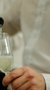 Gül şarabı bir garsonun elinde bardağa dökülür. Medya. Yakından şişenin boynu kaseye dökülüyor. Ağır çekim. Çerçevede yumuşak bulanıklık, canlı çekim. Şarap Degustation. Şaraphane konsepti