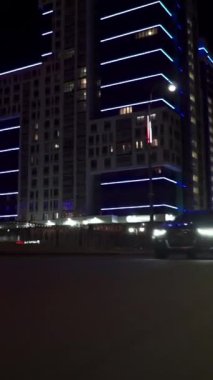 Şehirdeki bir gece caddesinde giden hızlı bir arabanın görüntüsü, ışıkların yüksek hızda arabaya yansıdığı bir yol. Modern bir şehrin hızlı ritmi.