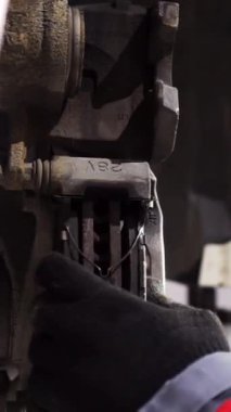 Tamir istasyonunda kaldırılan otomobilin tekerlek fren ayakkabılarını değiştiren araba tamircisi. Görüntü. Erkek ellerine yakından bak. Detaylarla çalış..