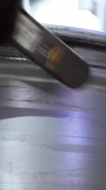 Lastik değiştirme ekipmanının metal yüzeyinin mekanik temizliği için tel fırça kullanan bir işçiye yaklaş. Araç servisinde çalışma sürecinin ayrıntıları.