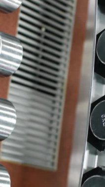 Salonda dambıllarla dizilin. Halterle birlikte kameranın raftaki hareketi. Medya. Spor için ağır metal spor ekipmanları.