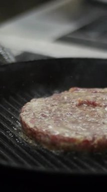Tavada kızarmış hamburger eti. Medya. Geleneksel Amerikan hamburgerinin evde mutfakta pişirildiği görüntüler. Akşam yemeği için yağda kızartılan taze kırmızı et pirzolasının video klibini kapat..