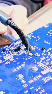 Çipi lehimleme, mühendislik işleri. Yazdırılmış devre kartındaki çiplerle çalışırken erkek ellerini lehim demiriyle kapat.