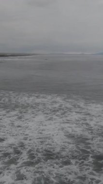 Bulutlu havada okyanus dalgaları. Görüntü. Kıyı şeridi boyunca deniz yüzeyi. Dalga sıçramaları. Doğa arkaplanı.