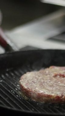 Tavada kızarmış hamburger eti. Medya. Geleneksel Amerikan hamburgerinin evde mutfakta pişirildiği görüntüler. Akşam yemeği için yağda kızartılan taze kırmızı et pirzolasının video klibini kapat..