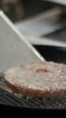 Sıcak tavada hamburger eti çeviriyorum. Medya. Geleneksel Amerikan hamburgerinin evde mutfakta pişirildiği görüntüler. Akşam yemeği için yağda kızartılan taze kırmızı et pirzolasının video klibini kapat..