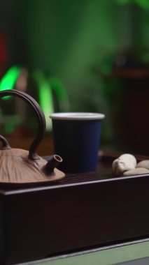 Bir çaydanlık, zarif bir fincan ve sakinleştirici yeşil ortam ışıklandırmasıyla güzel dekorasyonlar içeren sakin bir çay seti. Medya