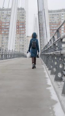 Soğuk bir kış gününde köprüde yürüyen bir kadın.