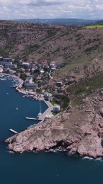 Dağlar arasındaki Akdeniz boğazındaki yatlar ve tekneler için rıhtım manzaralı bir yer. Stok görüntüleri. Kuşlardan inanılmaz bir şehir manzarası güzel bir kasabada yüksekten uçuyor.