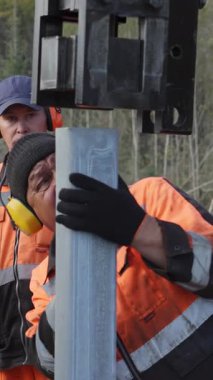 Güvenlik ekipmanları giymiş işçiler, yakınlardaki güzel bir orman bölgesinde sondaj görevleri yapıyorlar. Kırp
