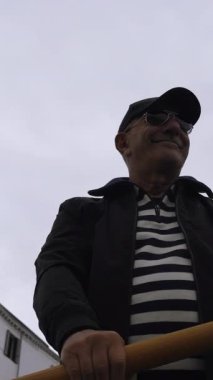 Gondolcular gondolları Venedik kanalından geçiriyorlar.