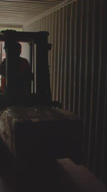 Bir forklift, endüstriyel lojistiğin karmaşıklığını gösteren yoğun bir konteyner koridorunda dikkatlice hareket ediyor. Stock Görüntüsü