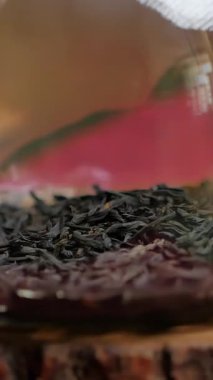 Kırsal bir ahşap masa üzerindeki cam çaydanlık rahatlatıcı yeşil çay dökme sürecini yakalar ve canlı çay yaprakları sergiler. Bu sakin sahne rahatlamaya davetiye çıkarıyor. Medya