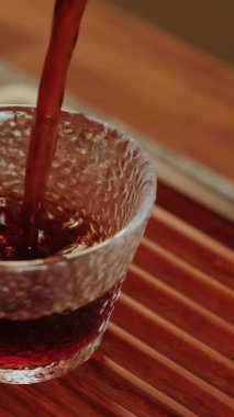 Zarif bir şekilde dokulu bir cam bardağa dökülen, renkli ve rahatlatıcı bir çay görüntüsü. Medya