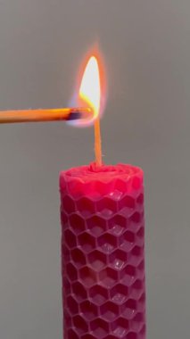 Tek pembe mum yanıyor. Vuruldu. Beyaz arkaplan mumu yanarken izole edilmiş. Kibrit mumu yakar, kibrit de mumu yakar. İlgi kavramı, karşılıklı yardım ve danışmanlık