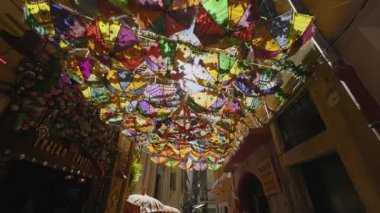 Şemsiyeler ve dekorasyonlar yayaların üzerinde asılı. Canlı ve kutlayıcı bir ortam yaratıyorlar.