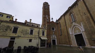 İnsanlar Venedik, İtalya 'da Campo San Barnaba' da bir kilise ve eski binaların yakınında dolaşıyorlar.