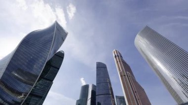 Moskova iş bölgesinde mavi gökyüzünü ve bulutları yansıtan modern gökdelenler