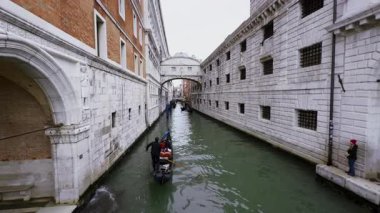 Turistleri taşıyan Gondol Venedik, İtalya 'daki iç çekiş köprüsüne doğru dar kanallardan ilerliyor.