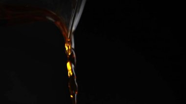 Enerjik sıvı akışına yakın çekim karanlık bir arkaplanda karmaşık şekiller ve çarpıcı yansımalar oluşturur. Medya