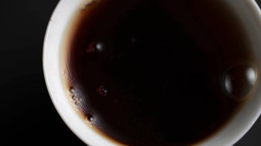 Yakın plan bir fincana sıcak çay döküldüğünü gösteriyor, kremalı bir girdap onun görsel çekiciliğini arttırıyor. Medya