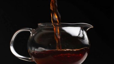 Cam çaydanlığa dökülen sanatsal bir çay sahnesi zengin rengini ve dokusunu güzel bir şekilde ön plana çıkarıyor. Medya