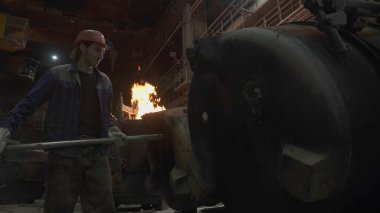 Bir dökümhanede kendini işine adamış bir işçi çelik üretim sürecinde endüstriyel becerilerini sergiliyor. Menkul Kıymetler