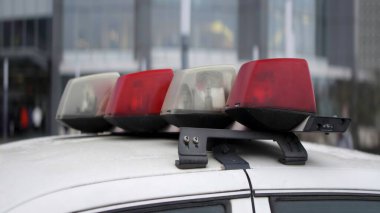 Polis arabasının çatısında kırmızı ve şeffaf polis ışıkları yanıyor.