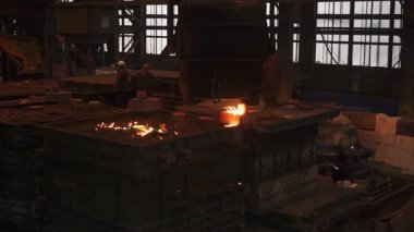 Çelik fabrikasında dökümhaneye erimiş metal döken işçiler