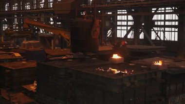 Dökümhane işçileri büyük bir endüstriyel fabrikada erimiş metali kalıplara döküyorlar.