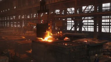 Çelik fabrikasında işçilerin kullandığı bir kalıba erimiş metal dökme süreci.