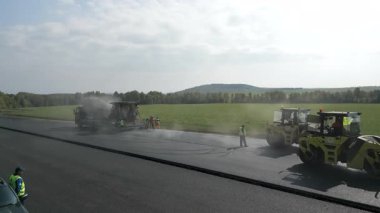 Yol silindirleri ve kaldırımlar yeni bir asfalt yolda çalışıyor