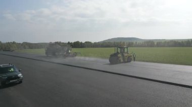 Yol silindirleri ve asfalt kaldırımlar yeni bir yol üzerinde çalışıyor